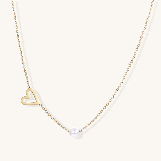 Dainty 14K gold-plated necklace with open heart pendant and white pearl bead on neutral background