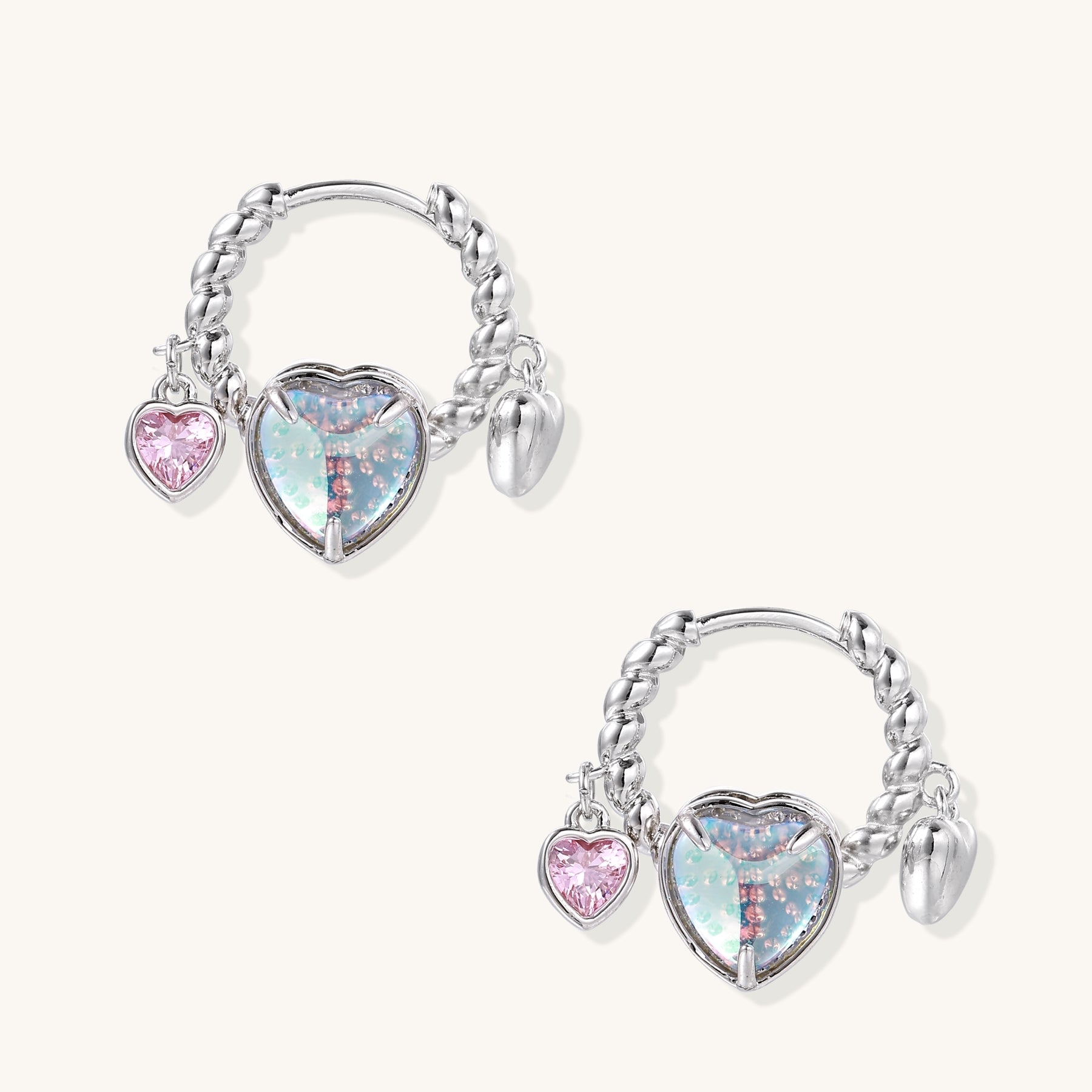 Gold-plated brass hoop earrings with three heart charms including iridescent turquoise and pink hearts on white background.