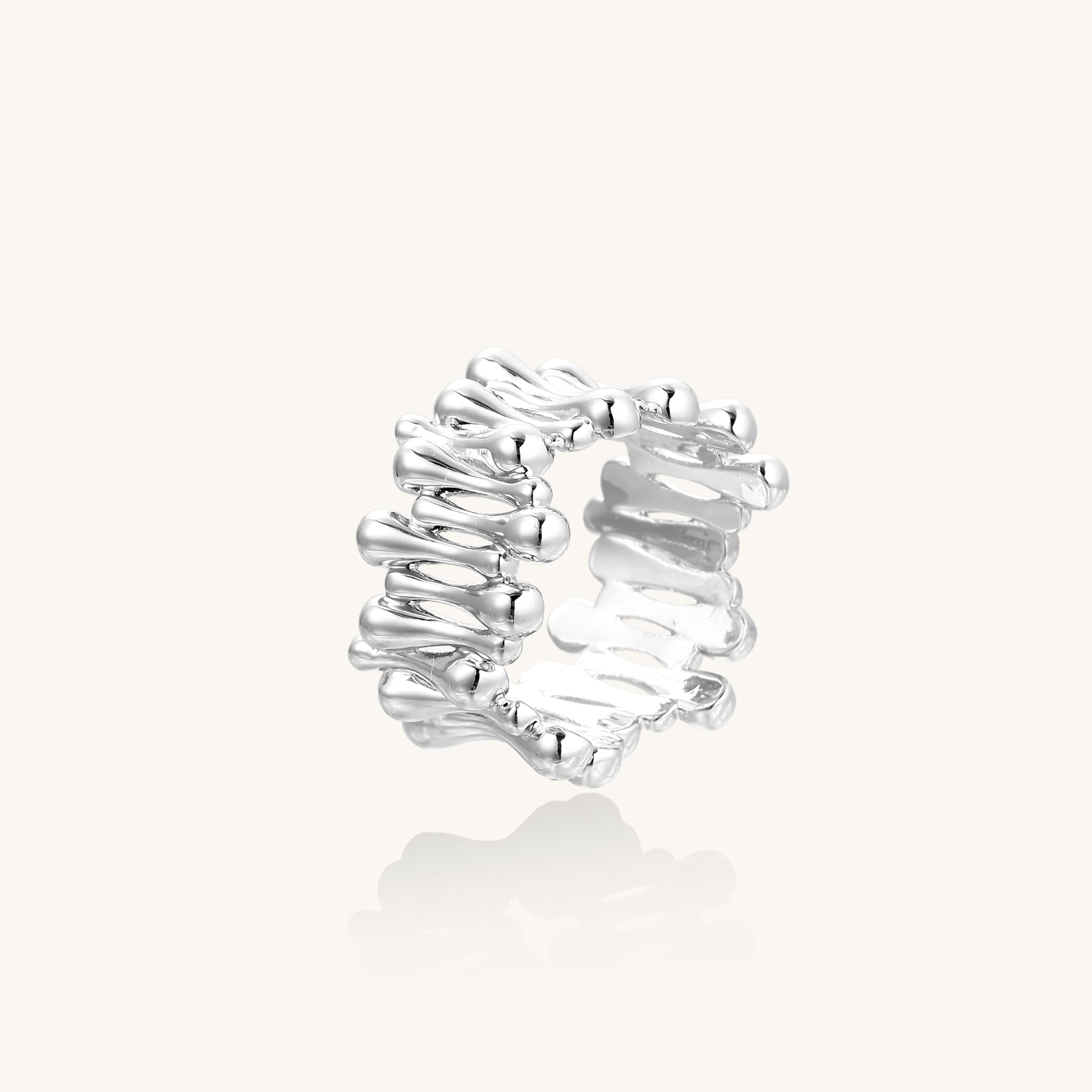 Close-up of an artistic gold-plated brass ring with multiple twisted bands creating a sculptural flowing design