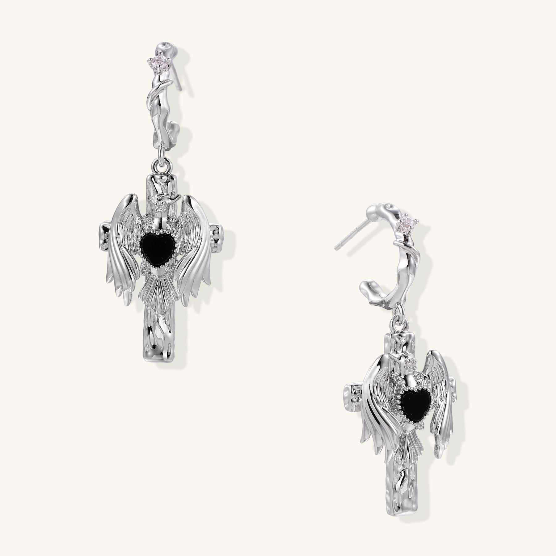 Gold-plated brass earrings with winged design, black heart-shaped zirconia center, and crystal accents on white background.