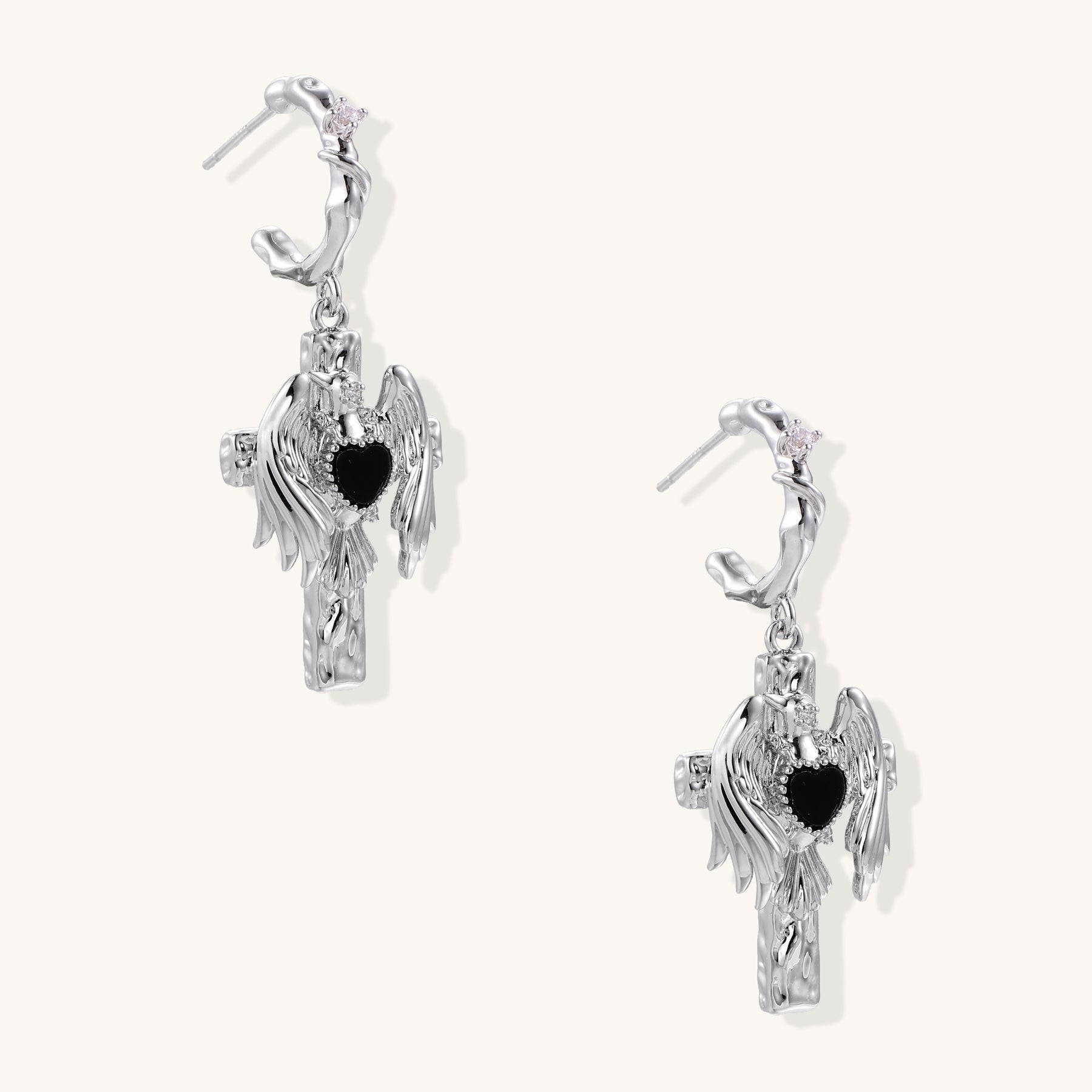 Gold-plated brass earrings with winged design, black heart-shaped zirconia center, and crystal accents on white background.