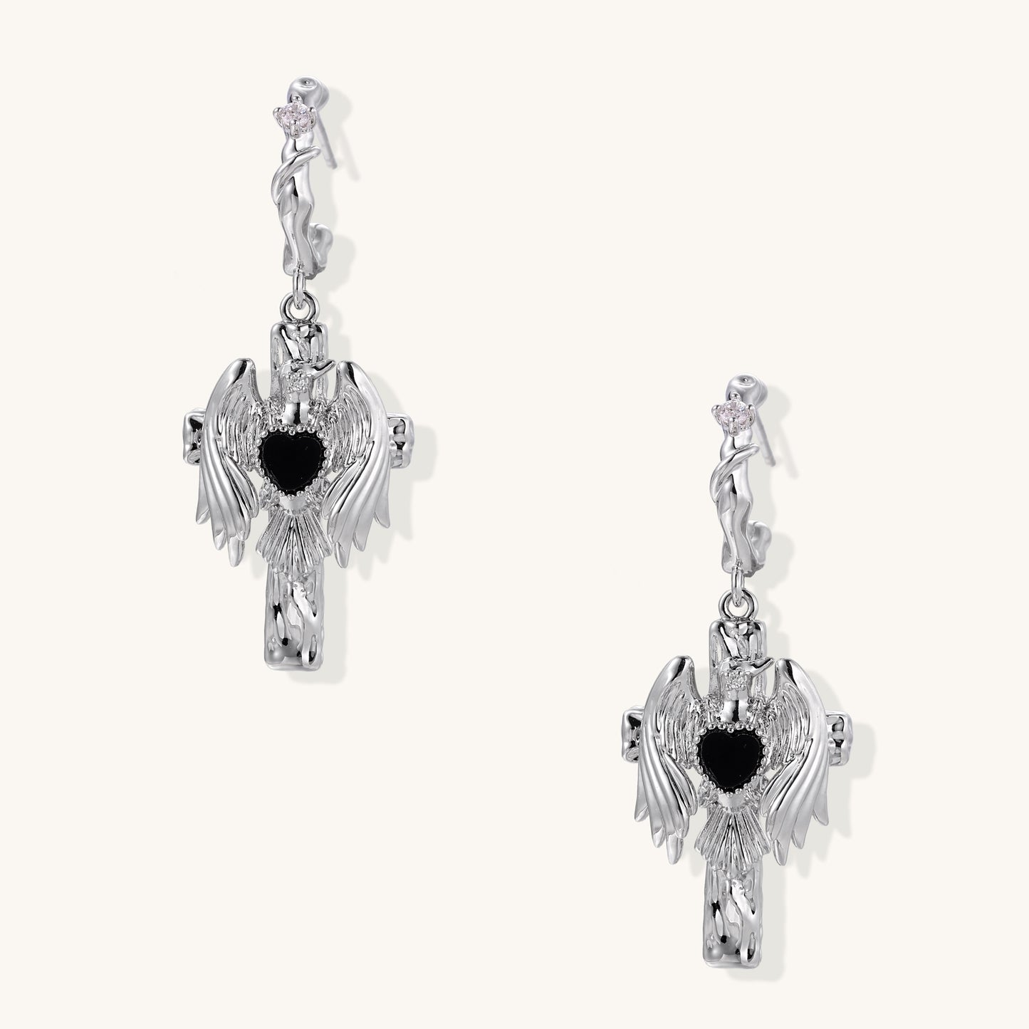 Gold-plated brass earrings with winged design, black heart-shaped zirconia center, and crystal accents on white background.