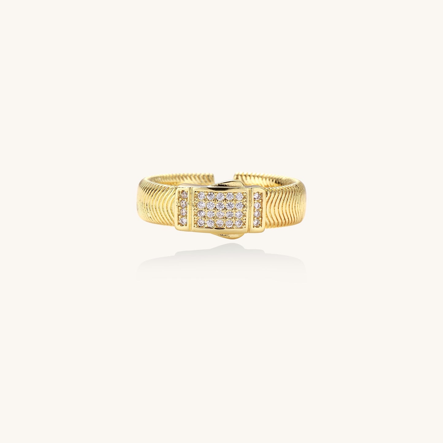 Gold-plated brass cuff ring with textured band and rectangular cubic zirconia centerpiece on cream background