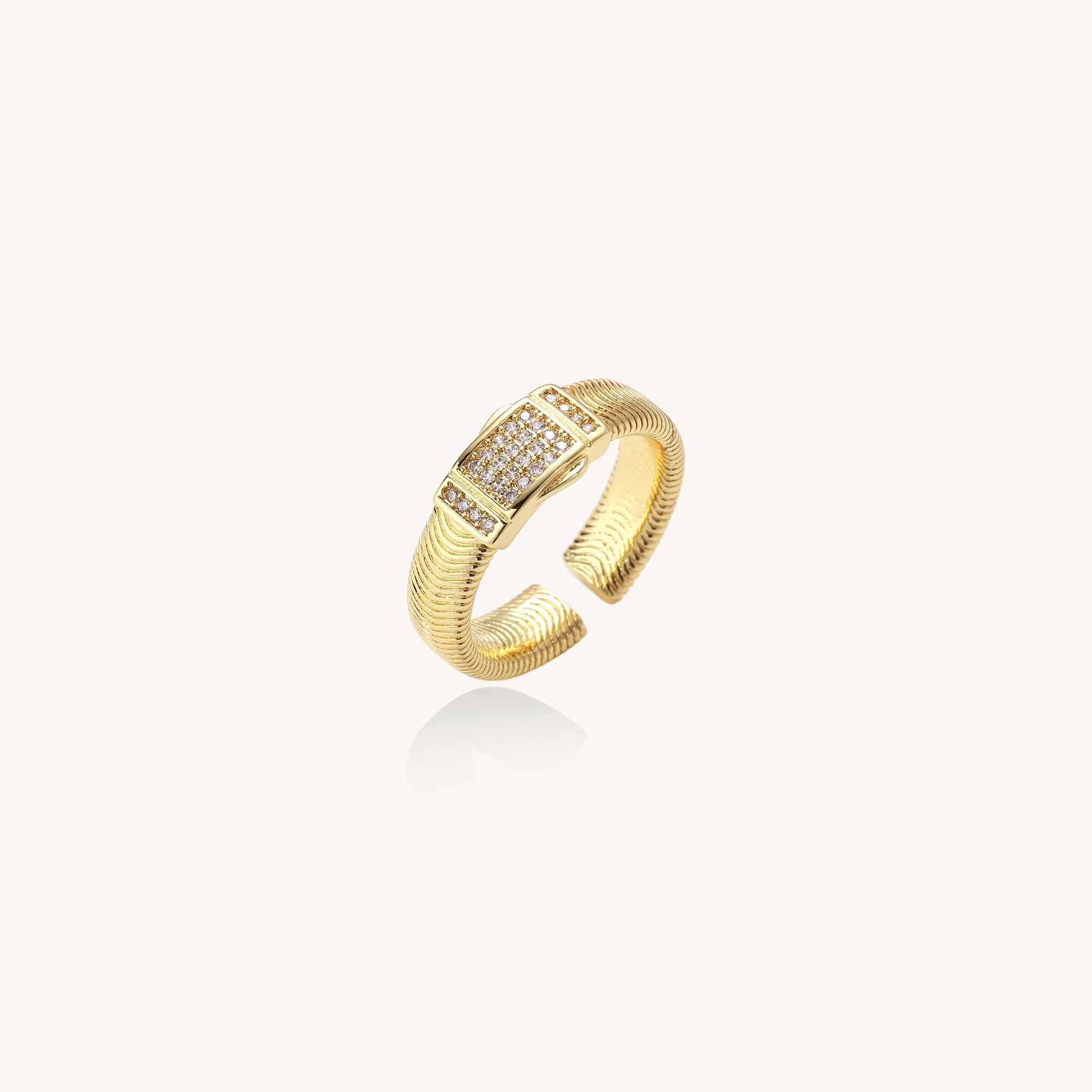 Gold-plated brass cuff ring with textured band and rectangular cubic zirconia centerpiece on cream background