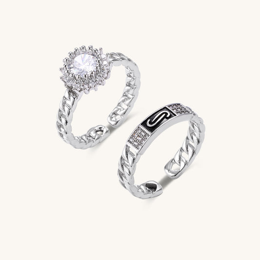 Two gold-plated rings with chain-link bands, one featuring cubic zirconia halo setting, displayed on neutral background