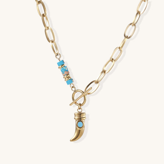 Gold-plated chain necklace with toggle clasp, turquoise beads, and curved horn pendant with inset turquoise stone on light background.