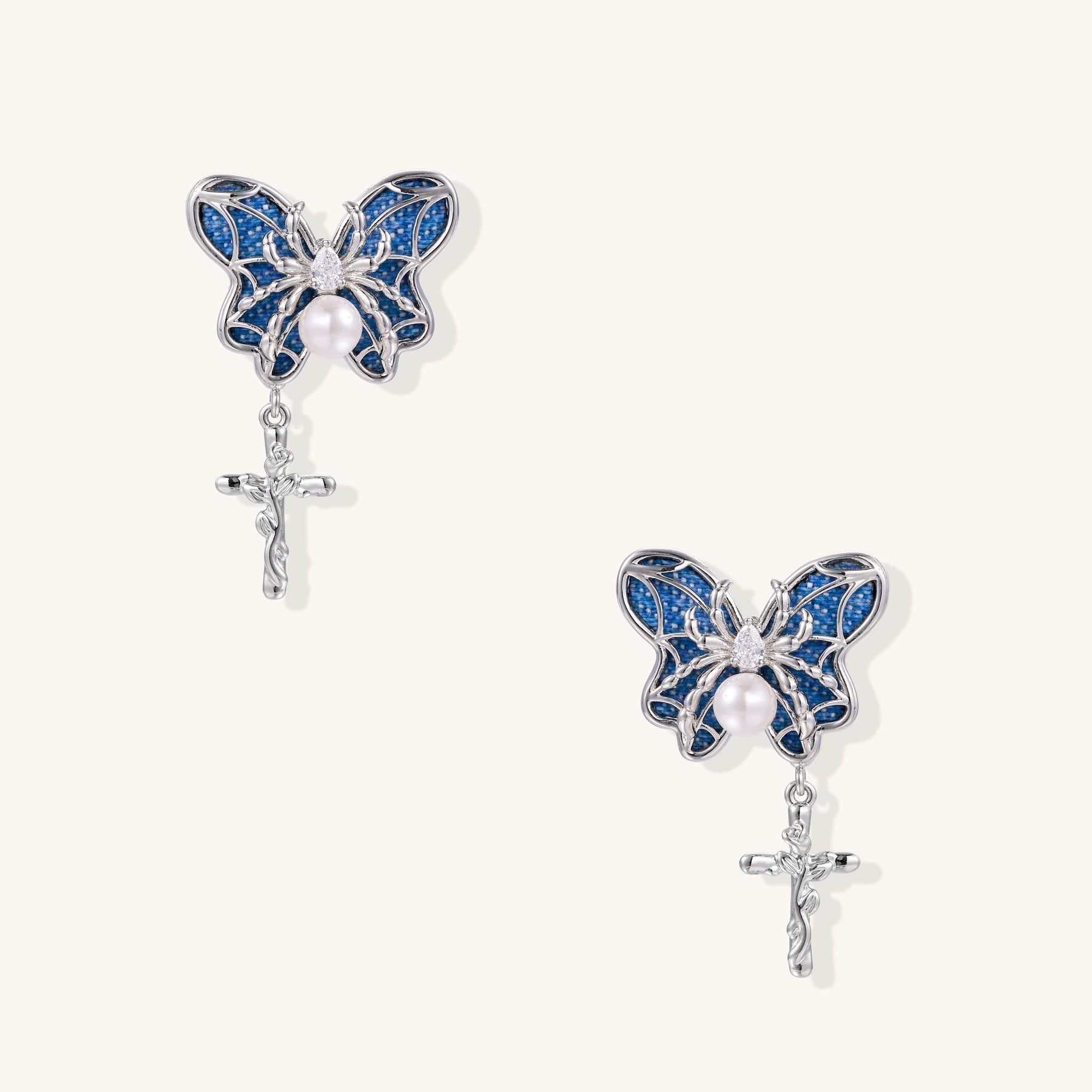 Ornate gold-plated butterfly earrings with blue enamel wings, white pearl centers, and silver cross dangles