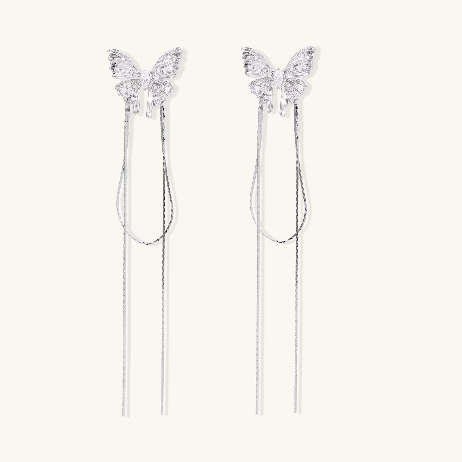 Delicate drop earrings with clear crystal butterfly tops and long metallic chain dangles on white background.
