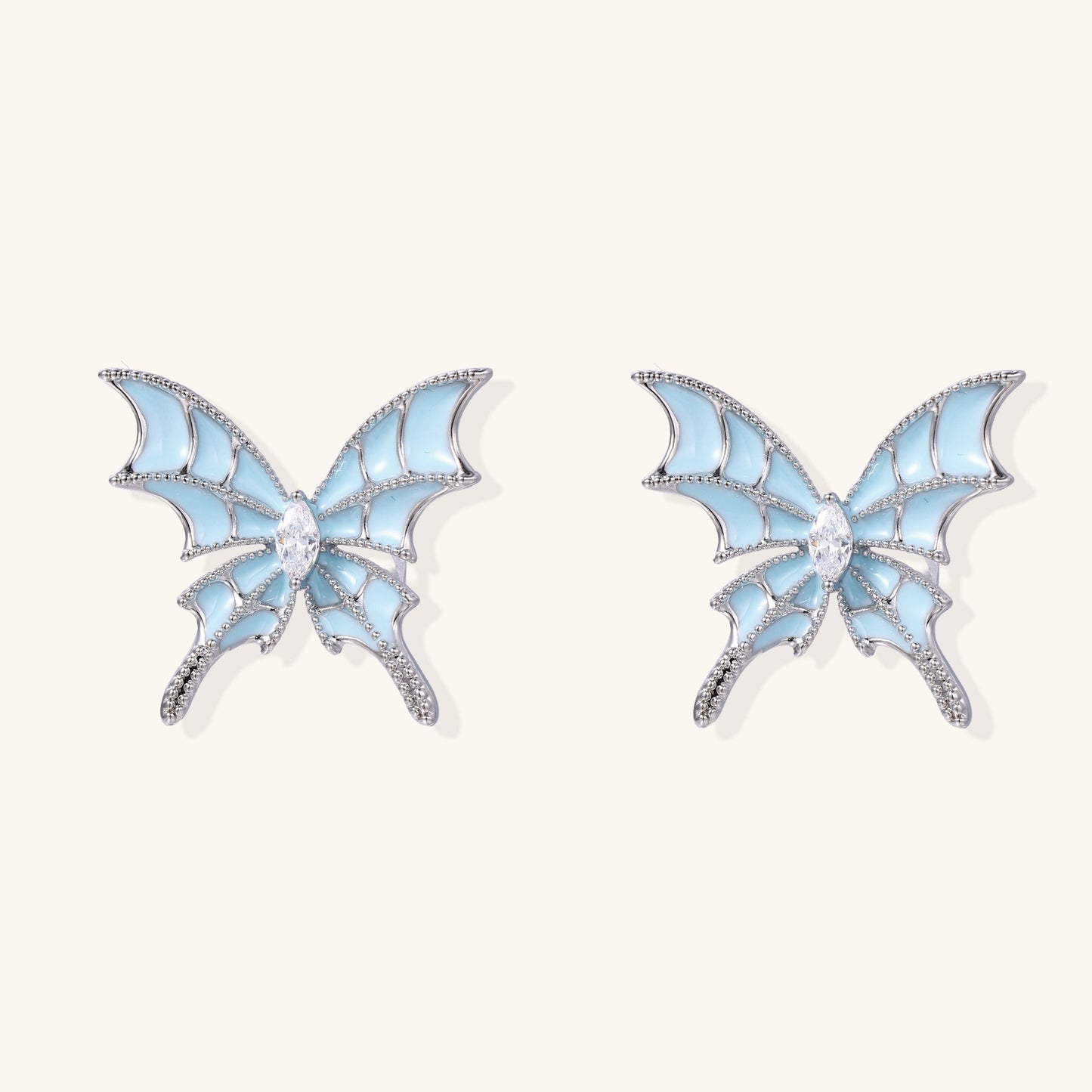 Blue enamel butterfly earrings with cascading gold-plated chains and zirconia crystal accents on white background.