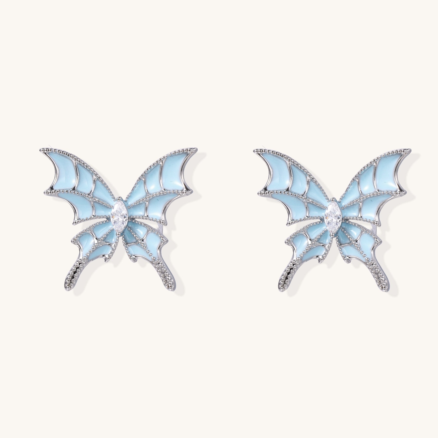 Blue enamel butterfly earrings with cascading gold-plated chains and zirconia crystal accents on white background.