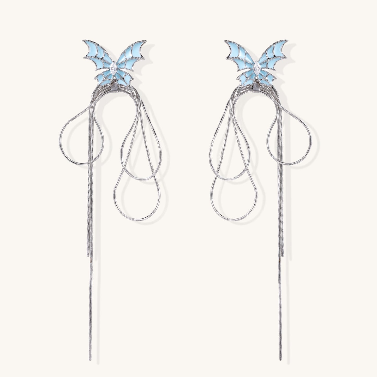 Blue enamel butterfly earrings with cascading gold-plated chains and zirconia crystal accents on white background.