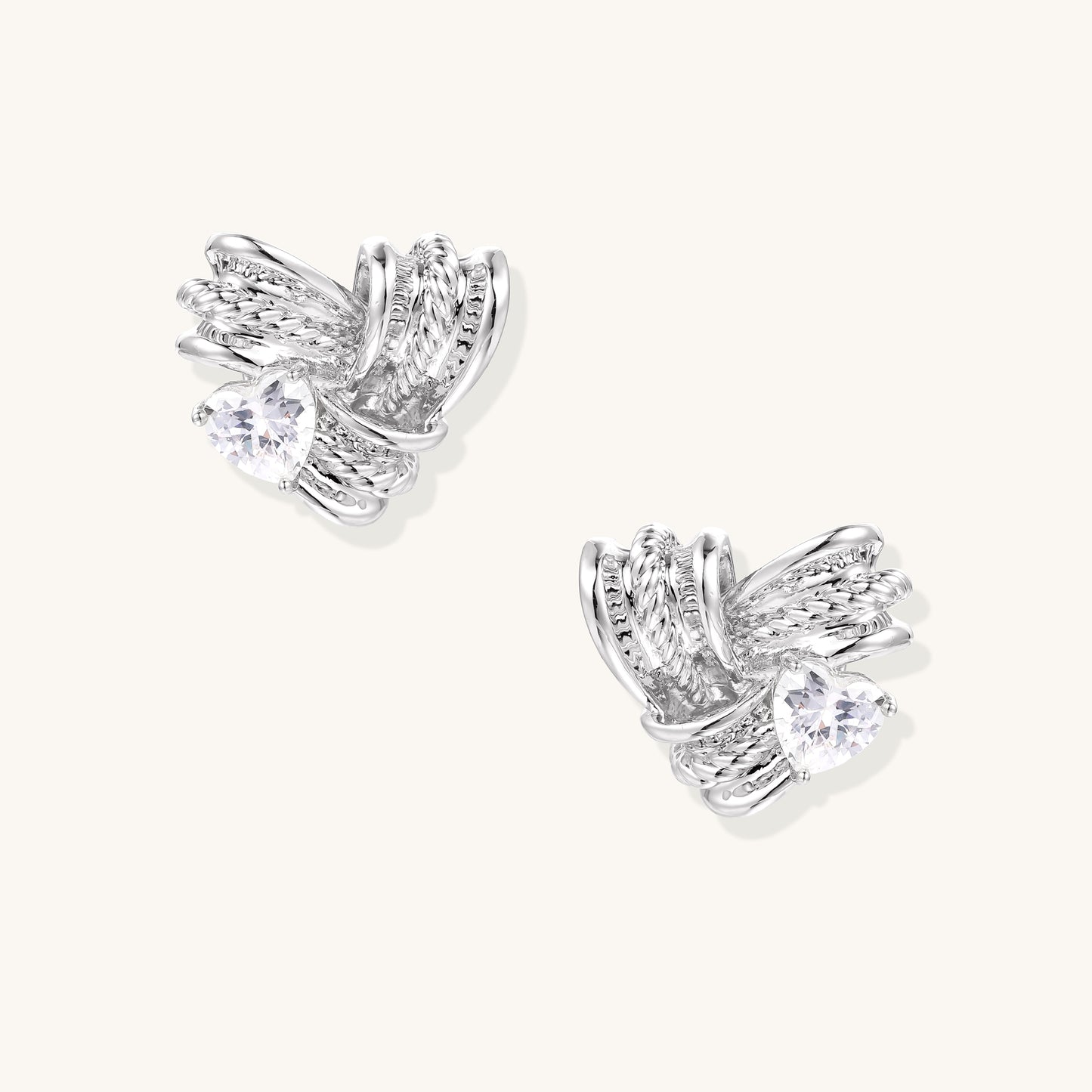 Gold-plated brass stud earrings with intricate twisted knot design and sparkling zirconia stones on neutral background.