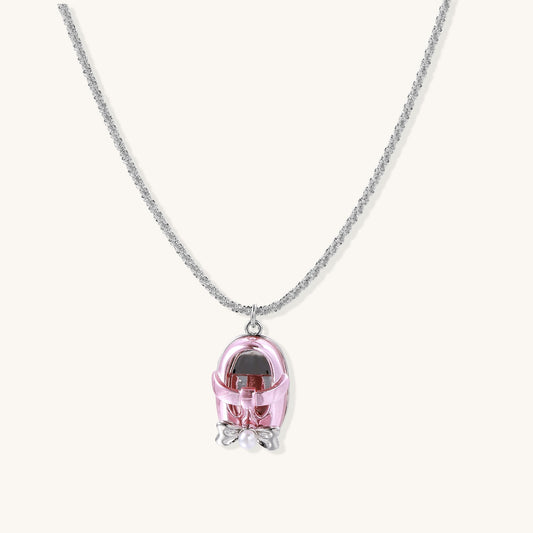 Delicate gold-plated chain necklace with transparent pink-tinted capsule pendant containing decorative bow element
