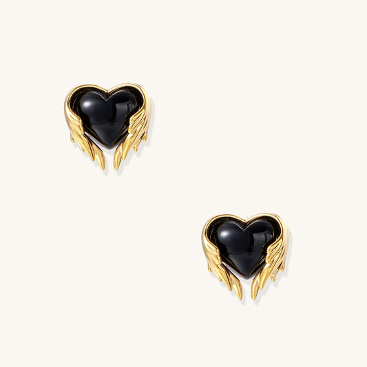 Pair of 18K gold plated earrings with wing design surrounding black resin heart centers on light background