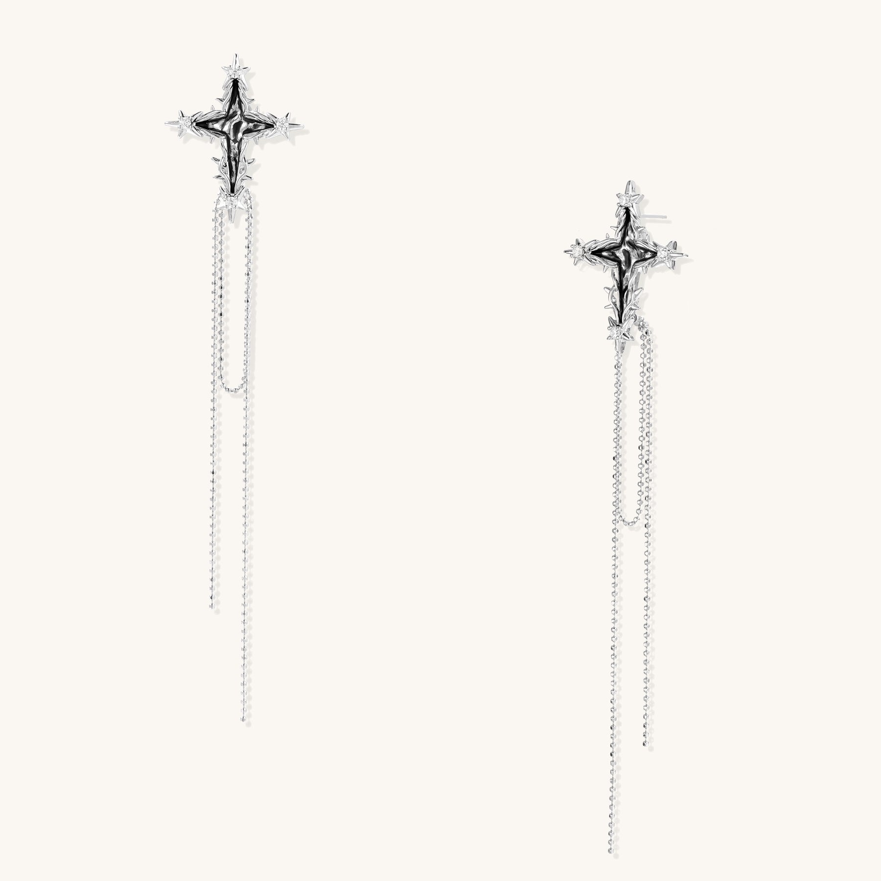 Long silver-toned cross earrings with star accents and delicate chain dangles on white background.
