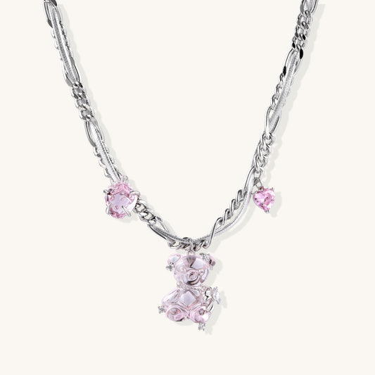 Adjustable gold-plated brass chain necklace with pink zirconia crystals and mixed link patterns on white background.
