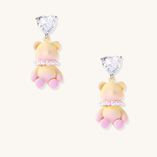 Cute teddy bear earrings with heart-shaped crystals, gold plating, and white pearl accents in pink and blue variants