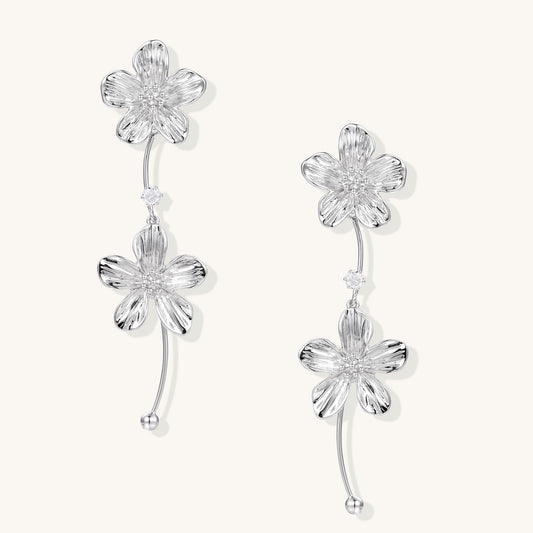 Gold-plated floral dangle earrings with zirconia crystal centers and curved stems on white background.