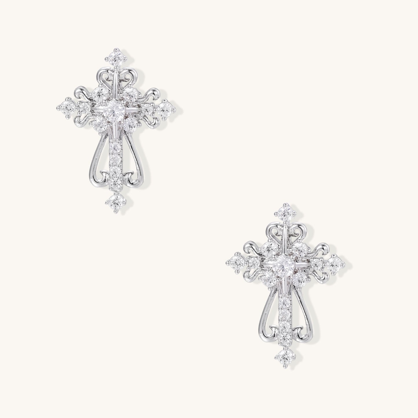 Ornate gold-plated cross dangle earrings with baroque scrollwork details and sparkling zirconia stones on neutral background
