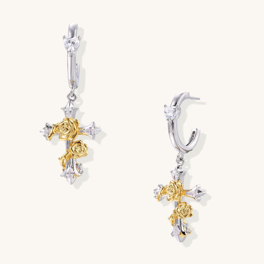 Gold-plated brass cross earrings with rose details and zirconia stones on silver hoops against light background.