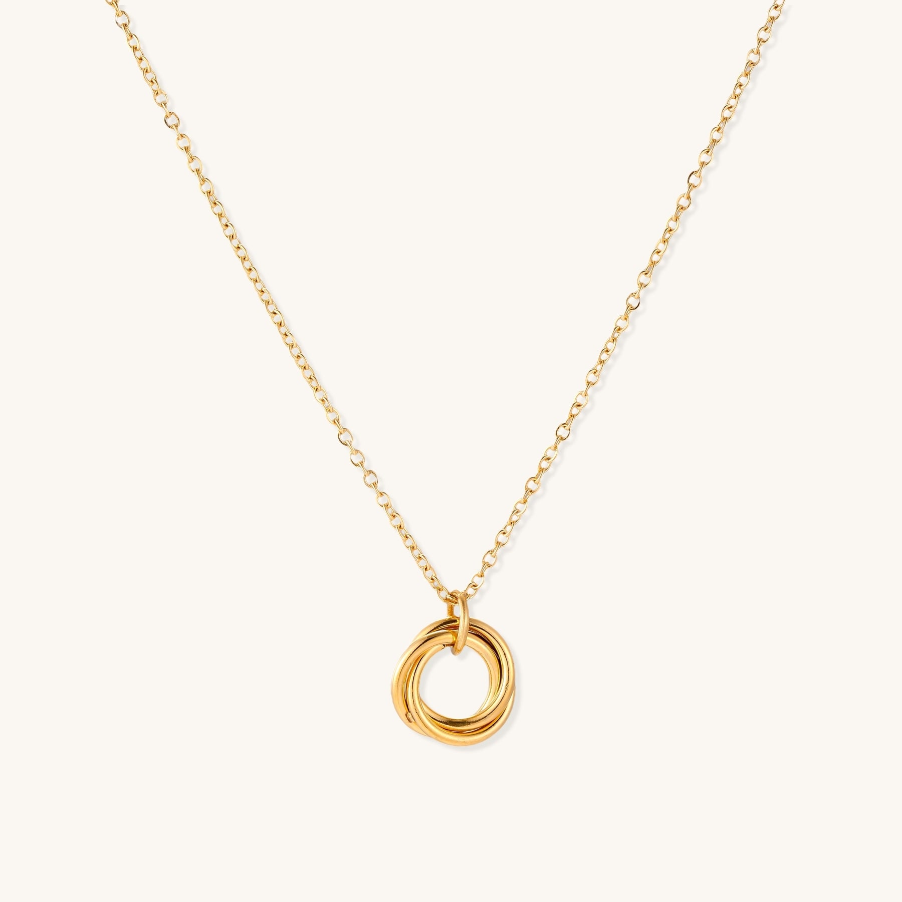 Close-up of a gold-plated stainless steel necklace with interlocking twisted ring pendant on white background