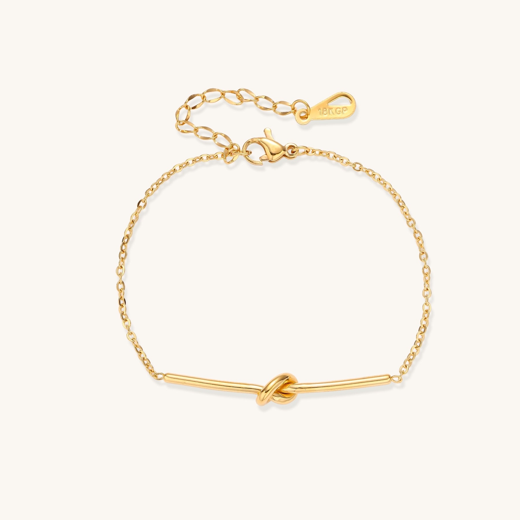 Delicate gold-plated chain bracelet with twisted knot bar detail and adjustable extender chain on white background.