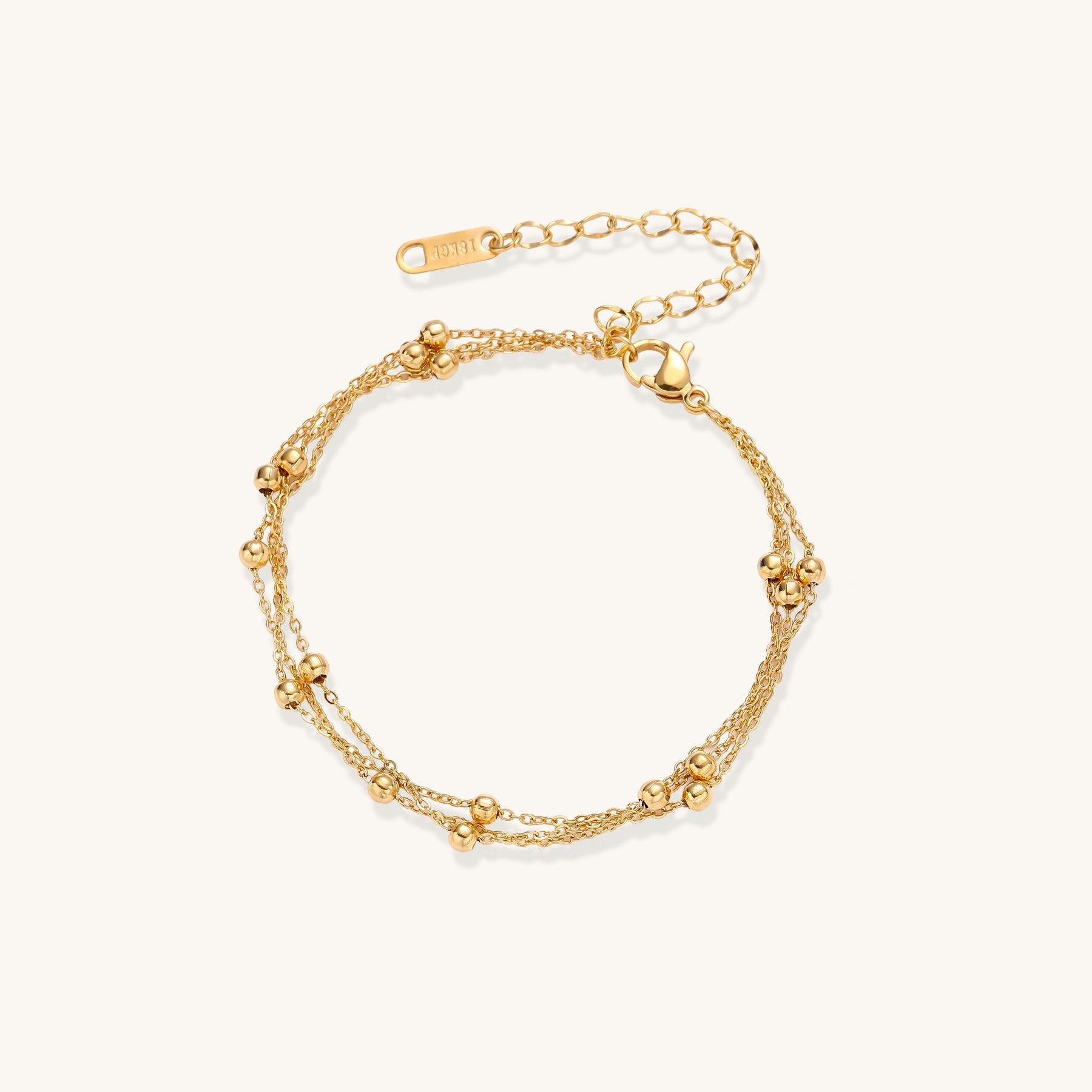 Delicate 18K gold plated bracelet with spherical beads on layered chains and adjustable extender on white background