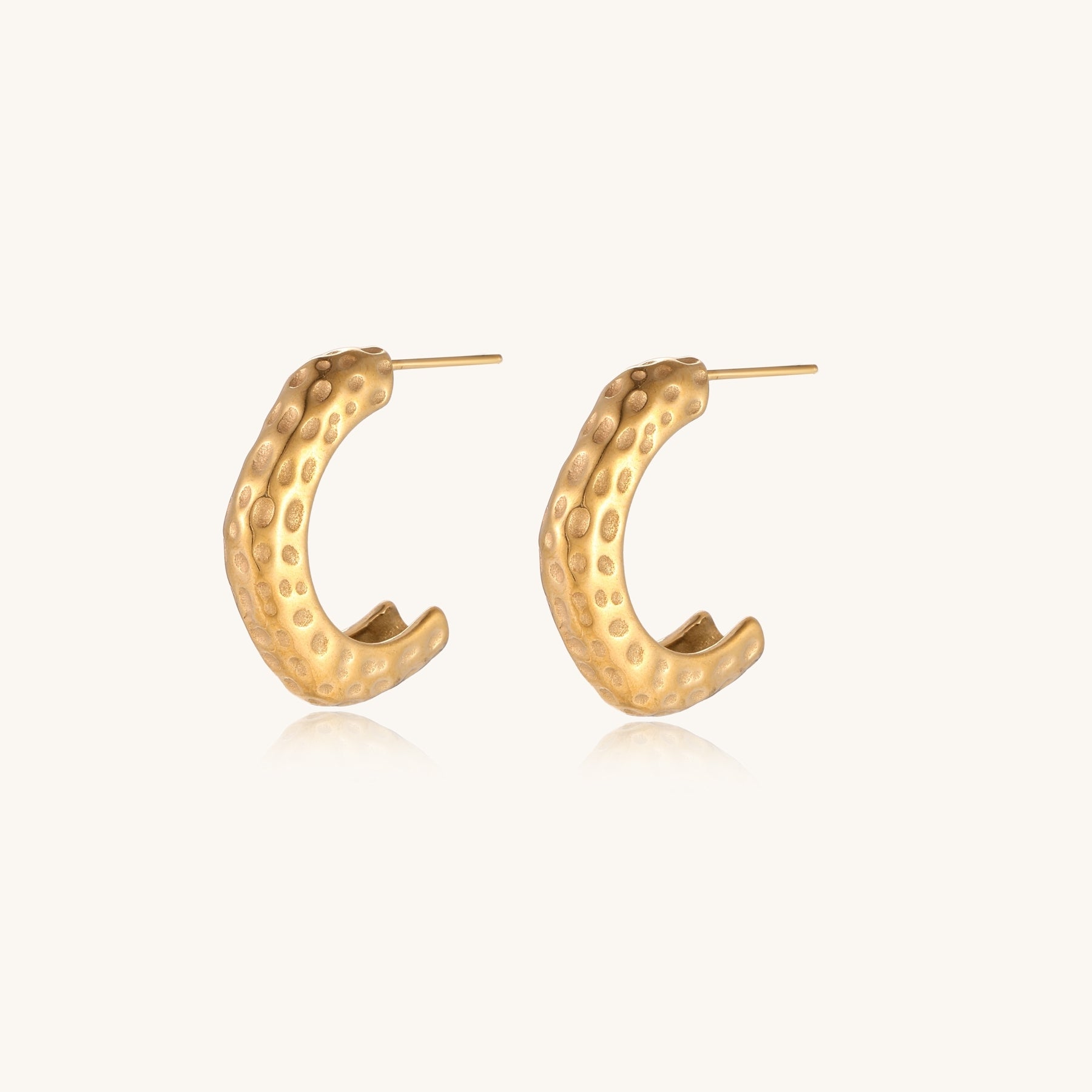 Textured gold-plated hoop earrings with dimpled surface pattern and post backs on neutral background.